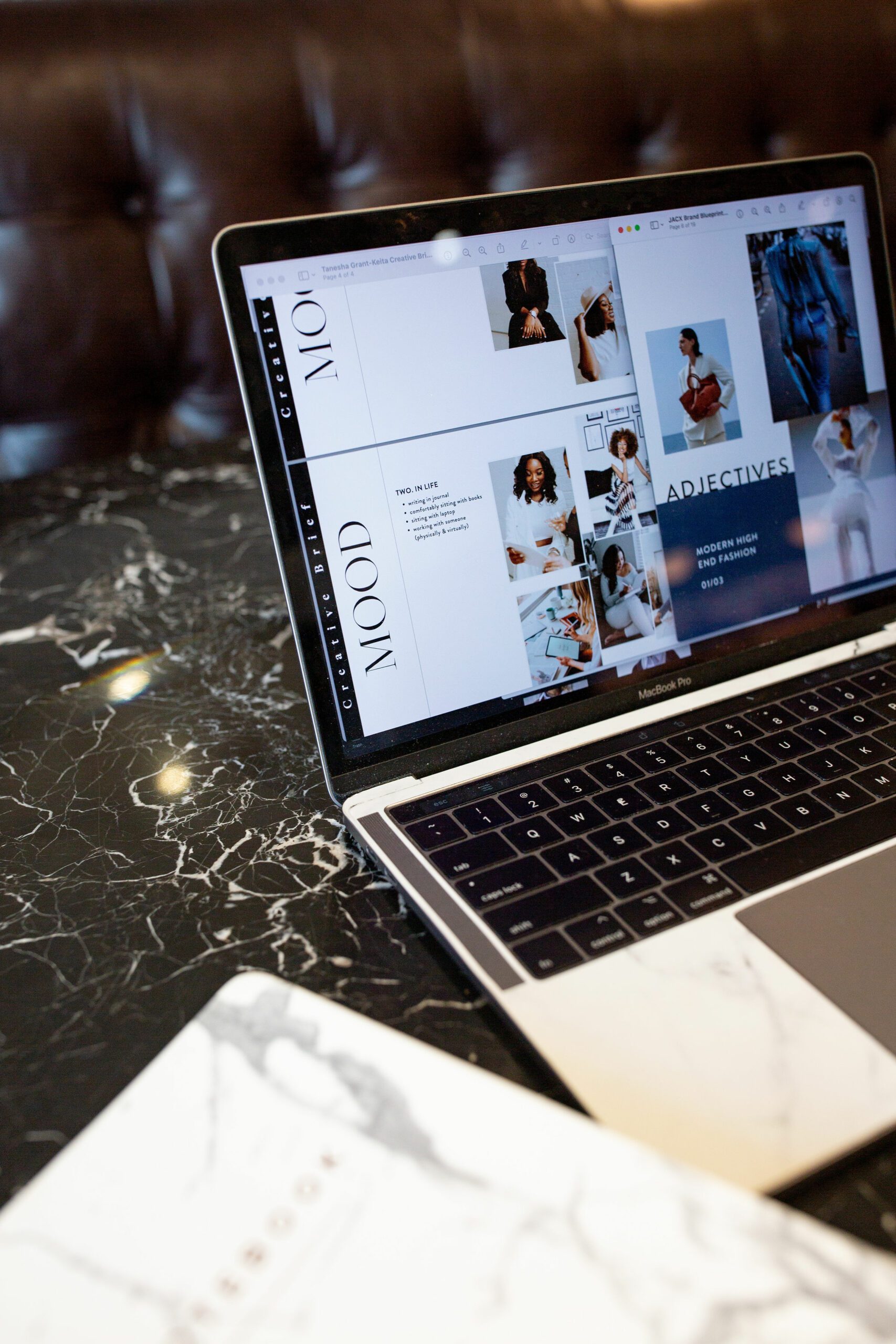 Silver macbook on marble table with the moodboard for a business displayed on the screen
