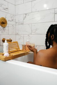 Black woman sitting in the bathtub enjoying self care