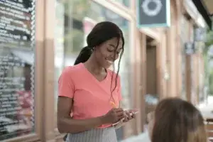 Woman in pink shirt writing down an order from a customer