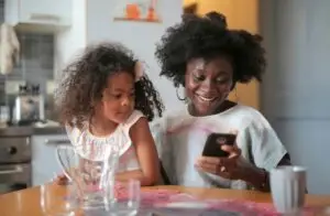 Two young girls sitting at a table looking at a cellphone