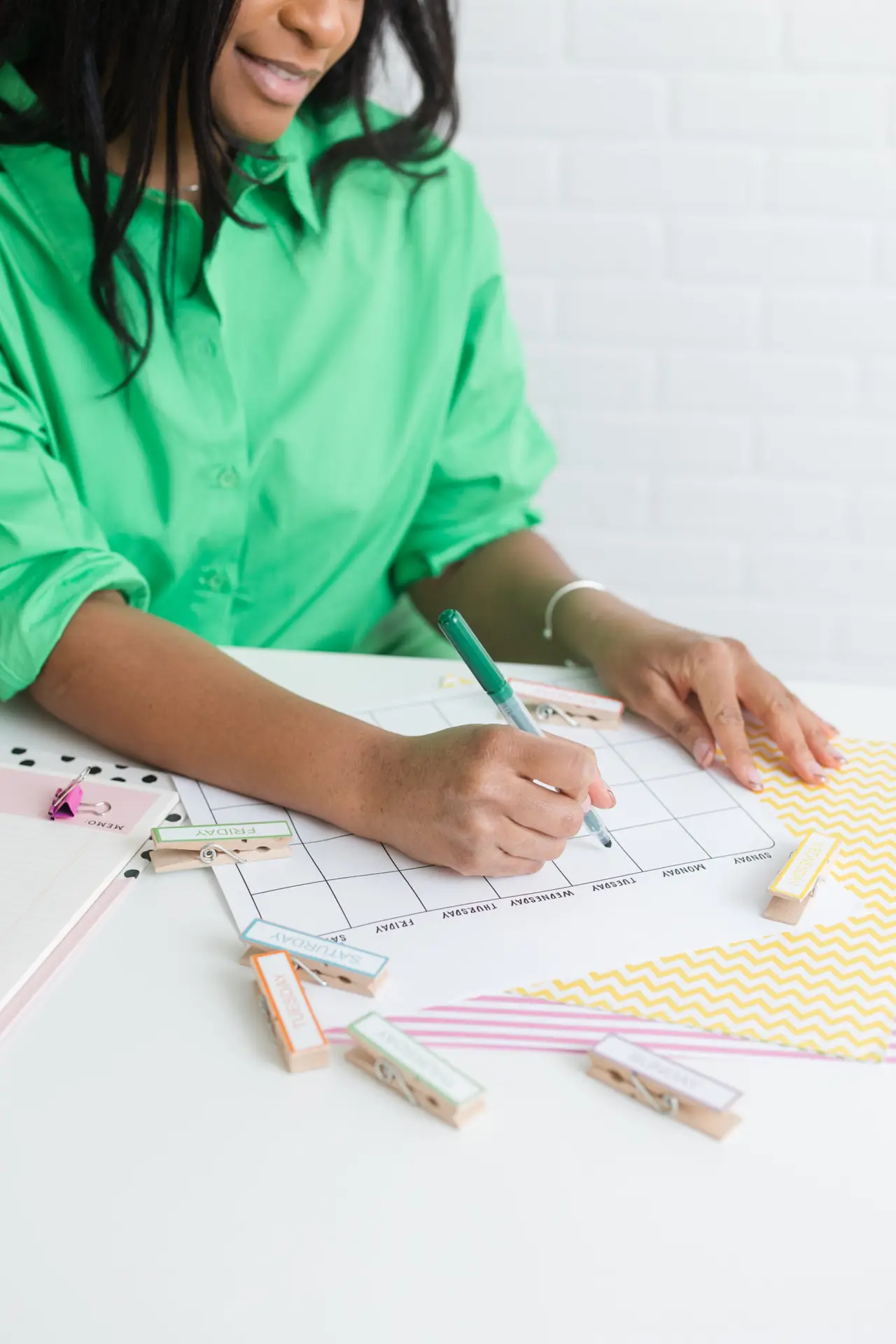 Woman in a green shirt writing on a calendar.