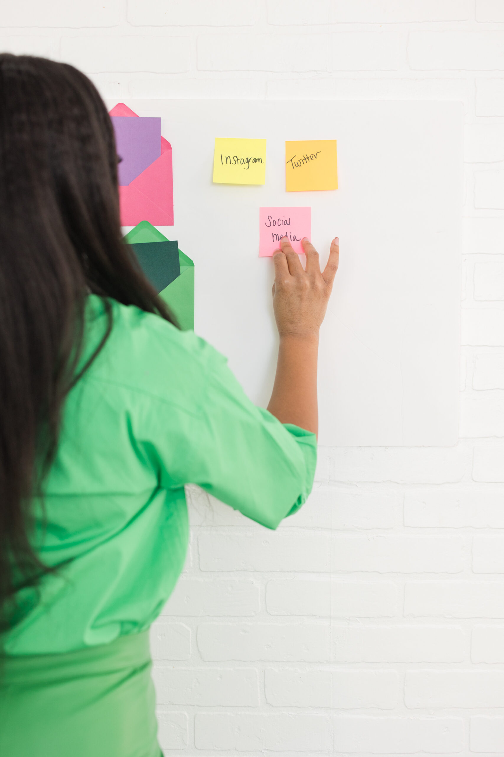 Woman in green shirt and green pant putting post it notes on the wall