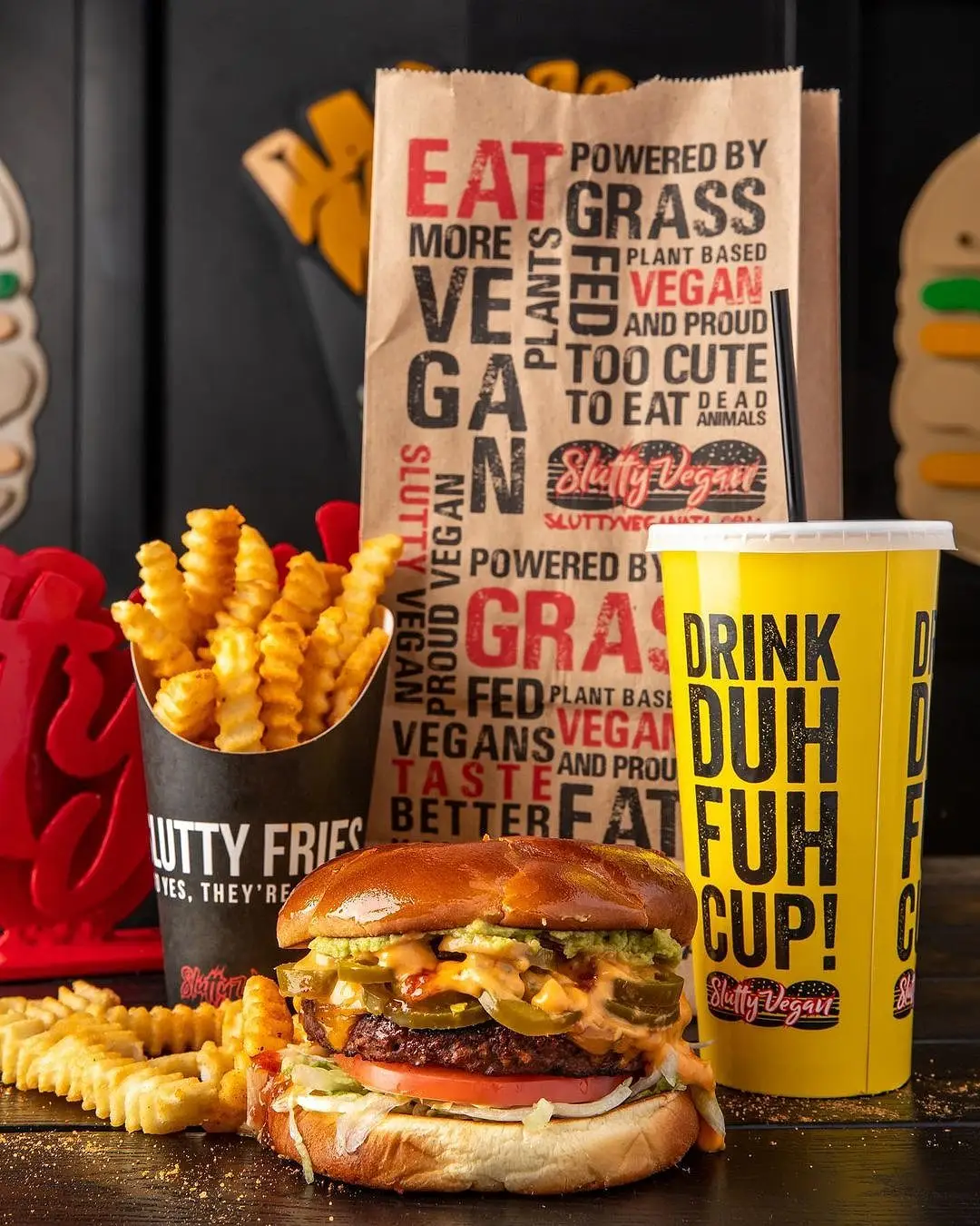 Vegan cheeseburger, fries, drink in yellow cup, brown paper bag